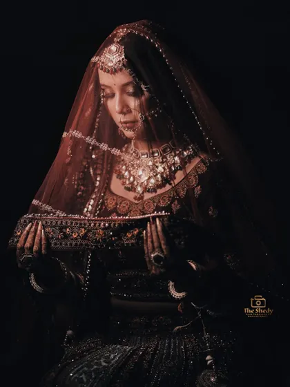 A close-up, artistic shot of the bride under her veil. The dramatic lighting creates a sense of intimacy and elegance.
