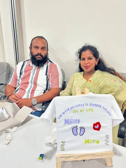 A couple with the personalized t-shirt they painted for their baby. It's a sweet and memorable activity for a baby shower.