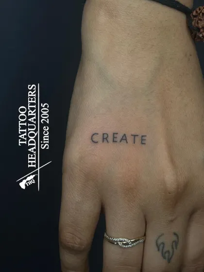 The word "CREATE" in a simple, clean font on the hand, a powerful one-word reminder for any artist or creator.