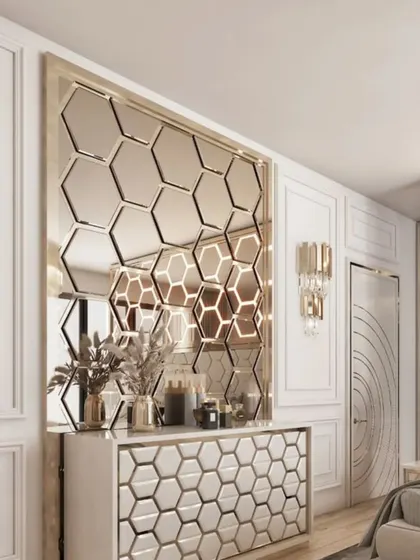 A glamorous wall design featuring a large mirror composed of hexagonal tiles, some of which are backlit. The matching console table has a 3D honeycomb pattern.