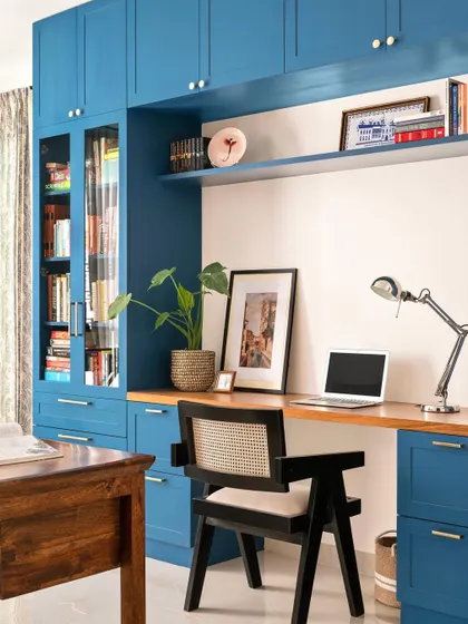 A full view of the home office with its striking blue library wall. The design provides extensive storage for books and files, along with a spacious desk area for daily work.