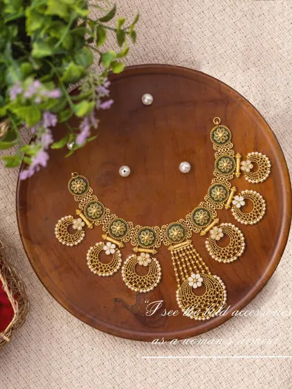 Styling a delicate pearl and gold necklace from Manjali Jewellers. The piece is laid on a simple wooden plate with scattered pearls and flowers, creating a serene and elegant composition.