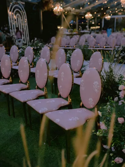 Custom-designed chairs with elegant pink upholstery, created specifically for Nidhi and Amit's ceremony. The floral motif on the fabric tied in perfectly with the surrounding garden installations.