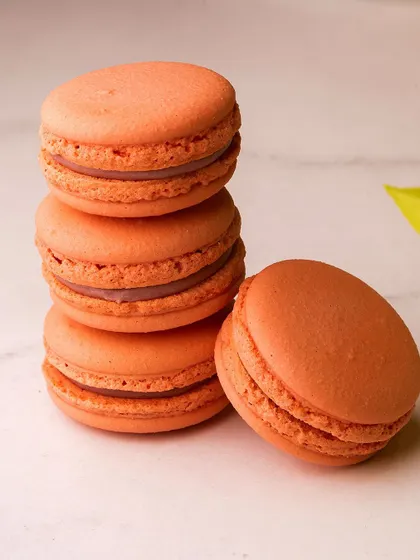 A stack of our orange macarons, perfect for adding a pop of colour and flavour to your day.