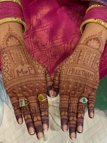 A close-up of the engagement mehendi, featuring the couple's initials "M P" and the groom's name, "Preetham."