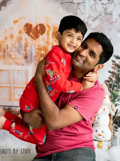 A big hug between a father and son. The snowy gingerbread house backdrop creates a magical, winter wonderland feel.