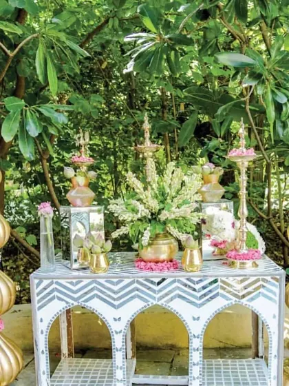 Detailed decor elements for a traditional Mehendi, featuring ornate brass props, mirror work tables, and beautiful arrangements of bougainvillea and other local flowers.