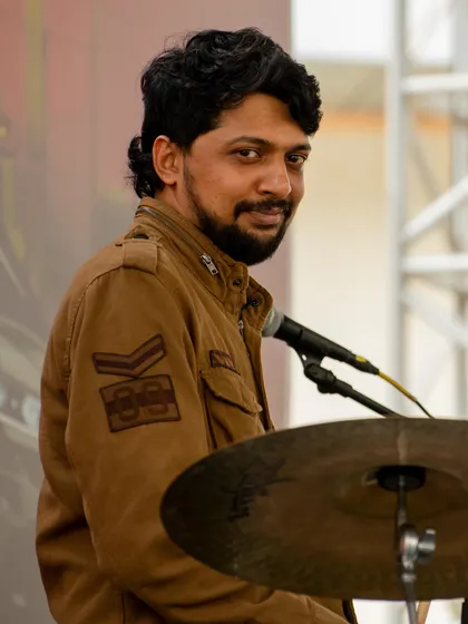 A quick smile from behind the cymbals catches our drummer between musical moments at Phoenix Marketcity.