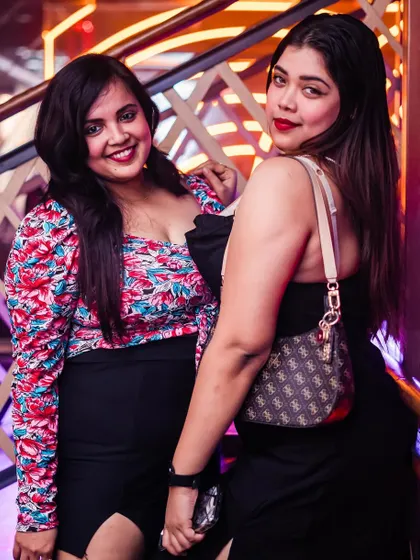 A stylish pair posing on the stairs of The Fixx, showcasing their party outfits.