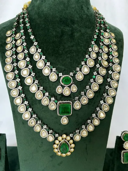 A layered bridal necklace set with three distinct strands, all featuring green stones and Kundan work. This rental set offers a very regal appearance.