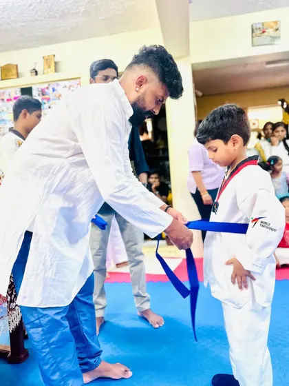 Tying a blue belt for this young student, marking his advancement to an intermediate level.