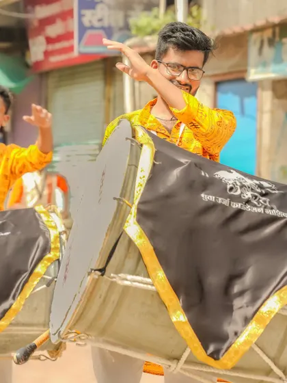 A dhol player with a smile and a playful gesture.