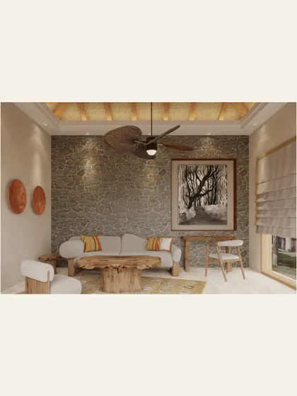 The living area of a villa in Kanha, designed as a comfortable retreat after a day in the wild. We used natural materials like a stone accent wall, a raw wood coffee table, and a woven ceiling fan to bring the textures of the surrounding forest indoors.