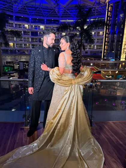 A stunning wide shot of the couple at their sangeet, with the bride's golden gown taking center stage.