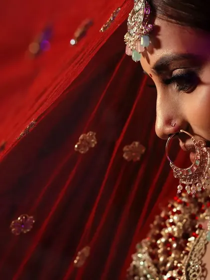 The true beauty of a bride lies in the eyes of the groom. This close up shot, with the red dupatta creating a soft frame, highlights her delicate features and bridal glow.