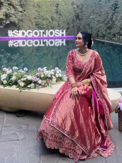 A stunning look for a wedding guest or the sister of the bride. This pink Banarasi weave lehenga features a hand-embroidered blouse and an opulent tissue drape for a touch of grandeur.