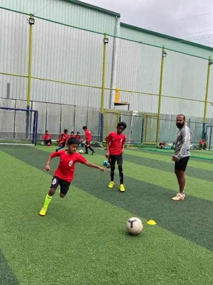 A young player executes a turn with the ball under the watchful eye of a coach during preseason training.