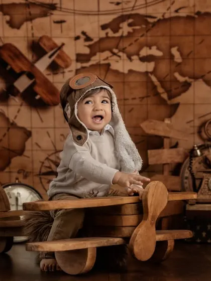 Adventure awaits. This little aviator is ready for takeoff in a vintage-themed shoot, complete with a wooden airplane, an old-world map, and classic props.