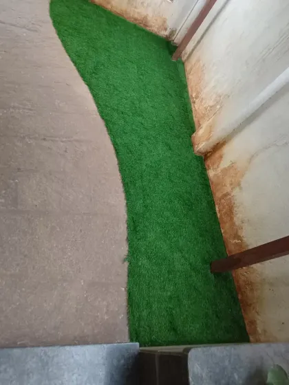 A view from above of the custom-cut artificial grass patch, showing how it fits perfectly into the unconventional shape of the space.