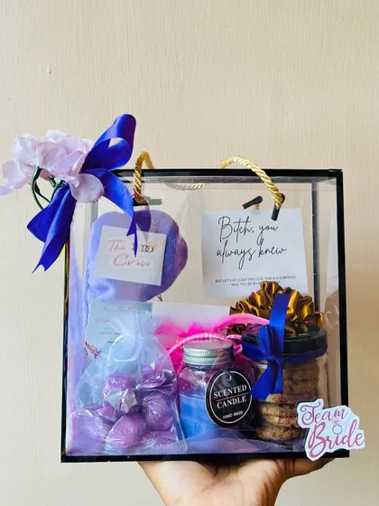 Holding up a finished bridesmaid hamper to show its convenient size and beautiful presentation. The purple theme is carried through from the ribbon to the items inside.