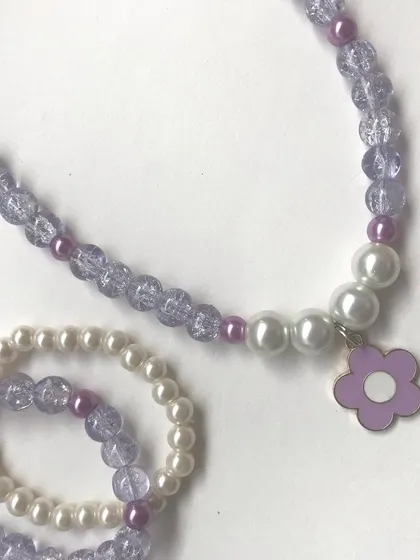 A clean, simple shot of the purple flower charm necklace and bracelet set. The combination of crackle beads and pearls gives it a lovely texture.