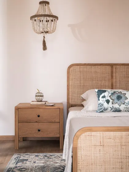 A detail of the primary bedroom, showing the beautiful cane bed and a beaded chandelier. The textures and materials were chosen to create a space that feels like a tranquil retreat.