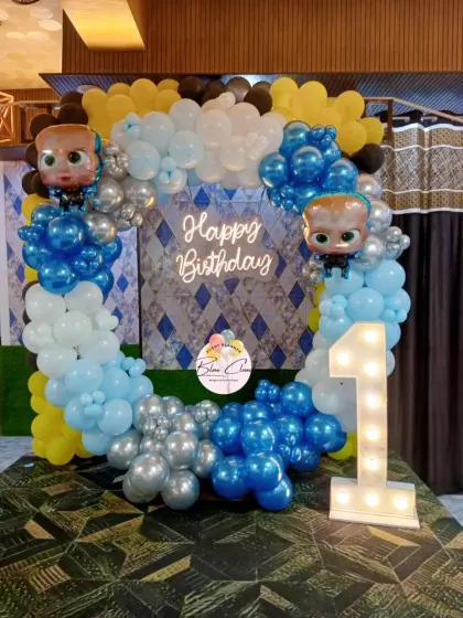 A Boss Baby themed first birthday with a square balloon frame, neon sign, and marquee number '1'.