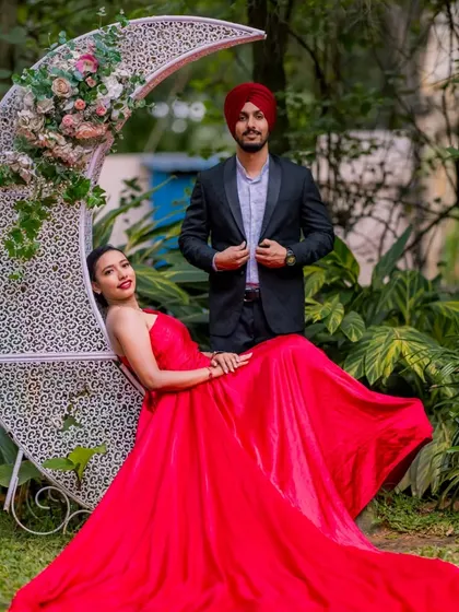 A classic fairy-tale pose with a crescent moon seat. The flowing red gown and the romantic garden setting make for a timeless and elegant pre-wedding portrait.