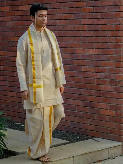 A quiet, contemplative portrait of the groom in his traditional dhoti and kurta, captured in a moment of calm before the ceremony.
