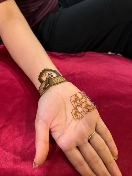 A simple combination of the initial on the wrist and the elephants on the palm.