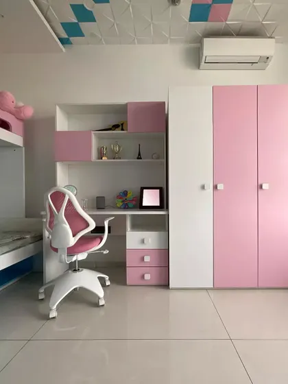 We design kids' rooms to be fun and functional. This room for a young girl uses a pink and white color scheme with a dedicated study area, ample storage, and an ergonomic chair, creating a perfect space for both play and learning.