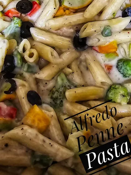 A close-up of our creamy Alfredo Penne Pasta, loaded with colorful vegetables and black olives. This is a popular choice from our customized snack boxes for birthday parties.