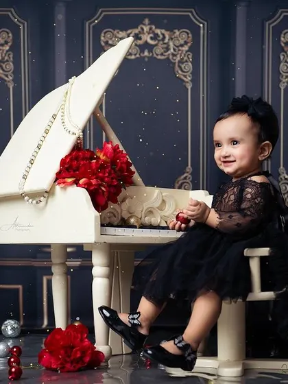 A happy smile from the birthday girl, seated at the piano during her glamorous first birthday session.