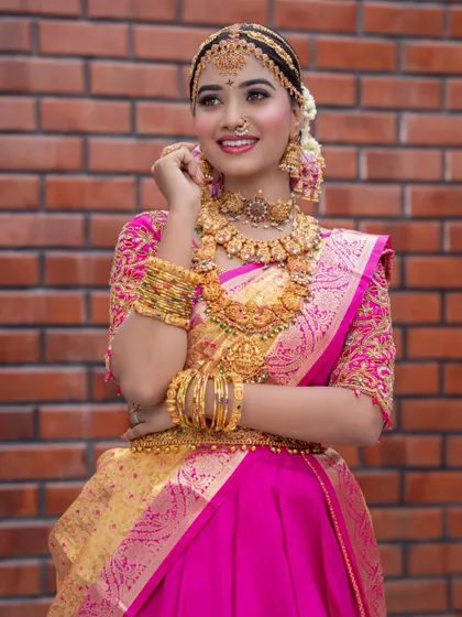 A happy and radiant shot of a model in a full bridal getup, wearing our complete temple jewellery set.