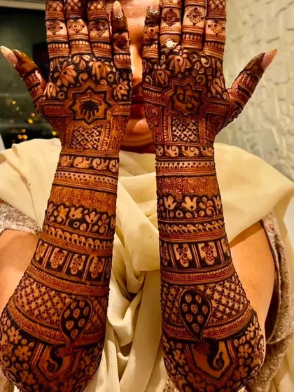 A classic pose showing off the full extent of a traditional bridal design. The patterns are symmetrical and feature elephants and peacocks.