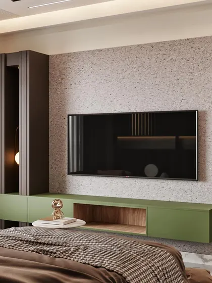 A bedroom TV wall design that combines a terrazzo-style finish with wood and olive green cabinetry for a playful yet modern look.