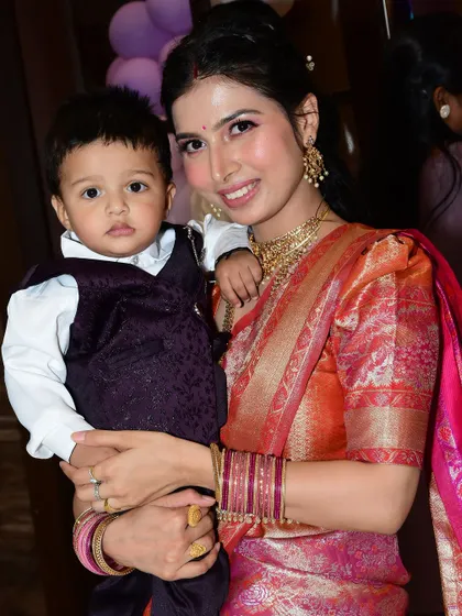 A beautiful moment shared by a happy client, looking radiant in her traditional saree at her son's birthday party.
