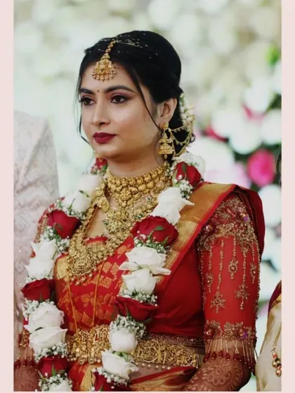 A bride looking radiant in her custom red blouse with intricate hand embroidery.