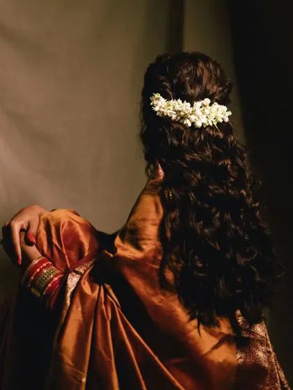 A beautiful shot focusing on the back of the bride, showcasing her intricate hairstyle adorned with fresh jasmine flowers. It’s a classic and elegant detail.