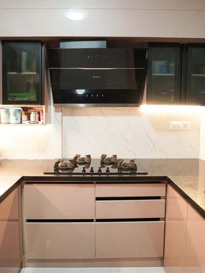 A close-up of the cooking area in the U-shaped kitchen, showing the modern chimney and marble-effect backsplash. The design is clean, functional, and perfectly suited for a contemporary home.