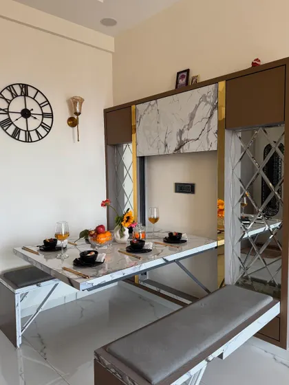 Here is one of my favorite innovations: a space-saving dining table that folds away neatly. This unit features a marble-finish tabletop, bench seating, and decorative mirror panels, making it perfect for compact Mumbai apartments.