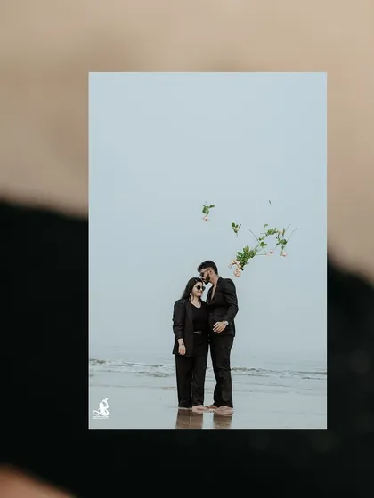 A creative shot of a couple on the beach, with a bouquet of flowers seemingly floating in the air.