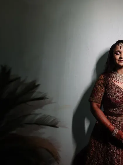 A full-length portrait of a bride at her reception, with her eyes closed in a moment of quiet reflection. The dramatic lighting adds to the elegance of the shot.