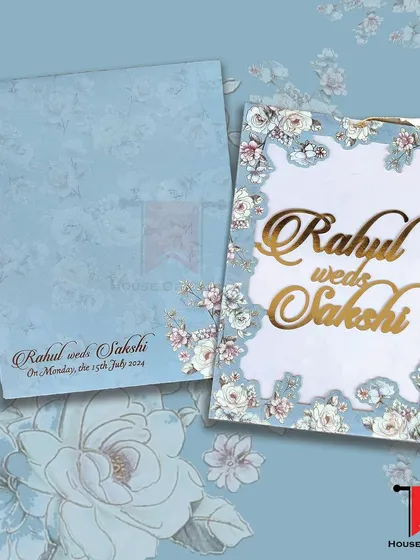 This laser-cut invitation features a blue floral frame with the couple's names in gold acrylic, creating a striking contrast.