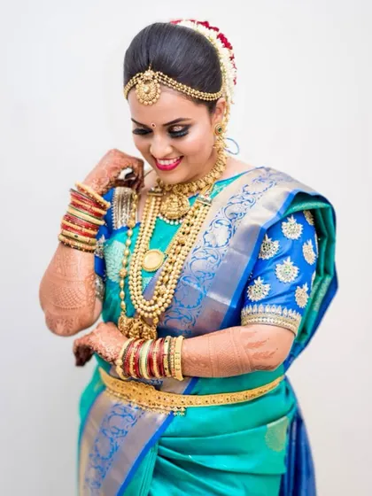 This South Indian bridal look is all about vibrant color. The bright blue and turquoise saree is balanced with flawless skin, a neutral lip, and beautifully defined eyes, letting the traditional jewelry shine.