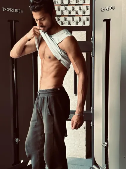 A classic ab-check pose in the gym. This is a staple shot for any fitness model, demonstrating core strength and low body fat.
