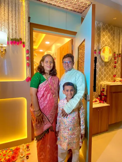 The Chaudhary family at the entrance of their new 2BHK home in Palava. The warm lighting and decorated doorway create a welcoming first impression.