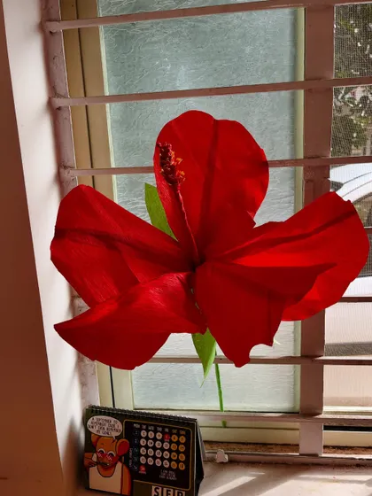 Even a single piece of decor can brighten up a room. Here’s our paper hibiscus catching the light by a window, showing how it can be a beautiful decorative accent in your home.