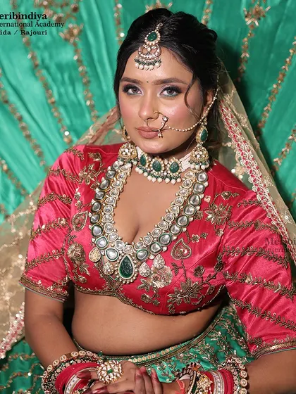 A close-up of a bride in a pink and green lehenga, with her hair styled in a classic updo to support the 'maang tikka' and dupatta.