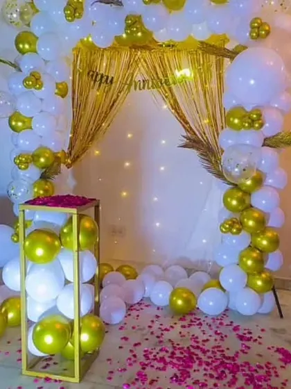 A close-up of the white and gold anniversary backdrop, featuring a golden curtain and fairy lights for a warm glow.
